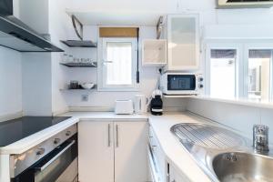 Una cocina blanca con fregadero y microondas. en Alohamundi Dúplex Alameda II, en Sevilla