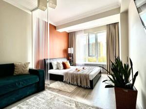ein Schlafzimmer mit einem Bett, einem Sofa und einem Fenster in der Unterkunft Просторные двухкомнатные апартаменты Терракота in Almaty