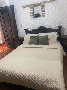 a large bed with white sheets and green pillows at Hotel Colonial Centro Historico in Tunja +12 photos