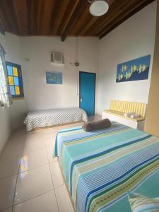 a bedroom with two beds with a striped blanket on the floor at Pousada Canto do Mar Ilha Grande in Praia de Araçatiba