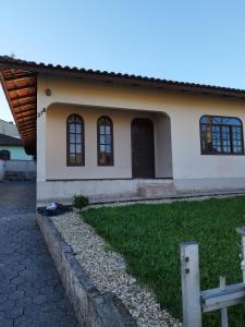 una casa con un patio de hierba delante de ella en Quarto privativo WC compartilhado, en Joinville