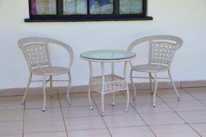 three chairs and a table with a glass table and two chairs at PS' COMFORT HOMES in Kakamega