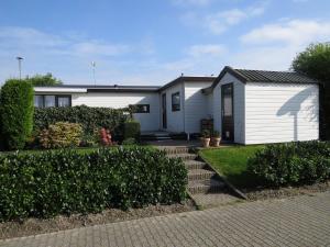 a white house with a garden and some bushes at Chalet Makkum V10 in Makkum