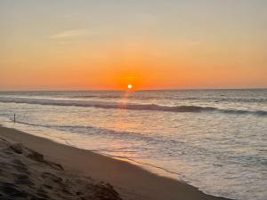 una puesta de sol sobre el océano con una playa con olas en Villa Aqua Boutique Vichayito en Vichayito