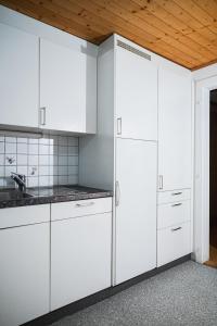 Il comprend une cuisine avec des placards blancs et un plafond en bois. dans l'établissement Glishorn Blick, à Brigue