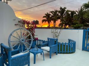 Villa Aqua Boutique Vichayito في فيشايتو: فناء مع الكراسي الزرقاء وعجلة aokedoked عند غروب الشمس