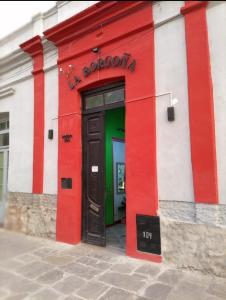 un edificio rosso e bianco con una porta verde di La Borgoña (Hostal) a Salta