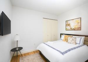 a white bedroom with a bed and a tv at Modern Two Bedroom At UES in New York