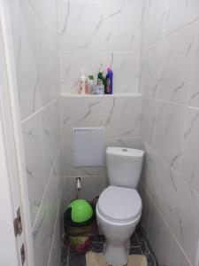 a bathroom with a toilet in a white tiled wall at Сдается 2-комнатная квартира в центре города in Atyrau