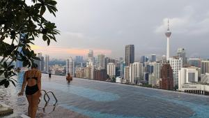 a woman standing on the edge of a rooftop overlooking a city at The Axon Suites Bukit Bintang KLCC By SKYSCRAPER in Kuala Lumpur