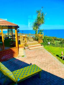 a yellow bench sitting on a brick patio near the ocean at Villa Mentone Hotel in Shanklin