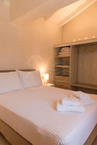een slaapkamer met een wit bed en handdoeken bij 8 Homes in Meganisi