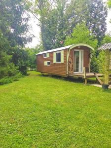 una pequeña cabaña en un campo de césped verde en La Roulotte à 10min de Disneyland Paris - Cabane & Cabanon, en Chalifert