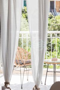 twee witte gordijnen op een veranda met een stoel bij 8 Homes in Meganisi