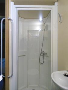 a glass shower in a bathroom with a sink at La Roulotte à 10min de Disneyland Paris - Cabane & Cabanon in Chalifert