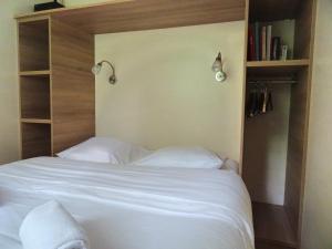 1 dormitorio con cama blanca y estante para libros en La Roulotte à 10min de Disneyland Paris - Cabane & Cabanon, en Chalifert