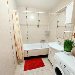 y baño con bañera, lavabo y lavadora. en Новобудова 2 кімнати Вернадського 8, en Leópolis