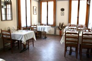 a dining room with tables and chairs and windows at La Petite Auberge in Versegeres 