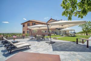 a patio with chairs and umbrellas and a house at Country House Giusti Abazia in Nervesa della Battaglia