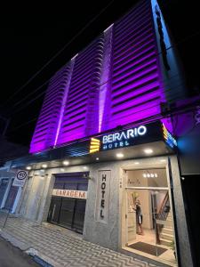 a person standing outside of a building with purple lights at Hotel Beira Rio in Teófilo Otoni