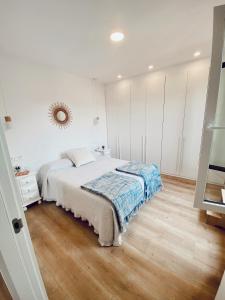 a white bedroom with a bed and a wooden floor at La bella Easo in San Sebastián