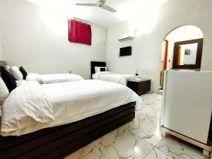 a white bedroom with two beds and a refrigerator at Swat Hilton Hotel by Khan Familia in Swat