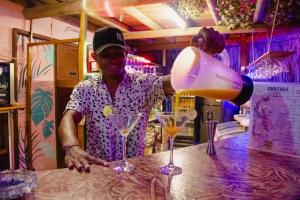 un hombre parado en un bar sirviendo una bebida en El Zoo Hostel, Bar & Pool, en Palomino