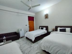 a hotel room with two beds and a ceiling fan at Swat Hilton Hotel by Khan Familia in Swat