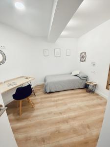 a white bedroom with a bed and a desk at La bella Easo in San Sebastián