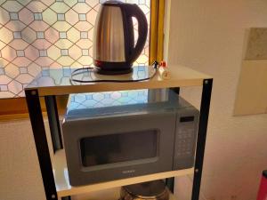 a microwave on a stand with a kettle on top of it at Apartamento Centricovive El Pulsar De La Ciudad in Toluca