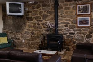 Una sala de estar con una pared de piedra con chimenea. en Casa A Chairiña y A Revolta, en Arnoia