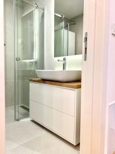een witte badkamer met een wastafel en een douche bij Bulevard17 in Belgrado