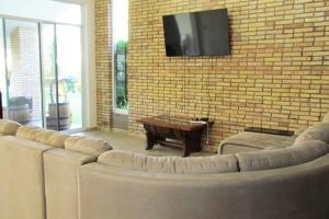 salon z kanapami i telewizorem na murze z cegły w obiekcie la casa de juanpi w mieście Atlixco