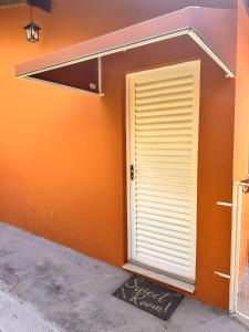 a door to a building with an orange wall at Sweet Room in Mogi Mirim