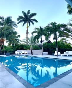 a swimming pool with palm trees in the background at Résidence de tourisme Domaine Saint-François in Saint-François