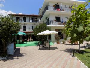 un edificio con patio con sillas y sombrilla en Des Roses Hotel, en Platanias