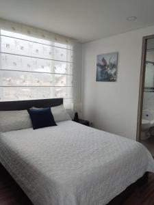 um quarto com uma cama branca e uma grande cabeceira de cama. em Hermoso apartamento con estacionamiento gratuito Chía N1 em Chía
