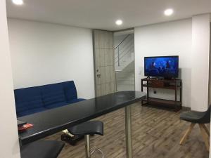 Hermoso apartamento con estacionamiento gratuito Chía N1 في شيا: غرفة معيشة مع أريكة زرقاء وتلفزيون