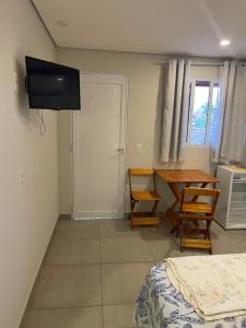 a room with a bed and a table and a television at Anexo Marques in Paraty