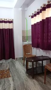uma sala de estar com cortinas roxas e uma mesa em Darbar Homestay em Gaya