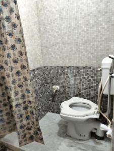 a bathroom with a toilet and a shower curtain at Darbar Homestay in Gaya