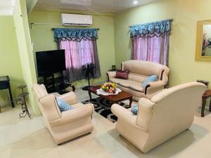 a living room with white chairs and a tv at St Eldo in Arima