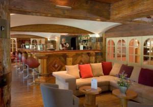a living room with a couch and a bar at Residence Le Domaine du Jardin Alpin - Courchevel 1850 in Courchevel