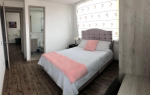 Hermoso apartamento con estacionamiento gratuito Chía N1 في شيا: غرفة نوم بسرير ومخدات وردية ونافذة