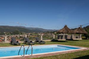 Una piscina con sillas y vista a una ciudad. en Casa A Chairiña y A Revolta, en Arnoia