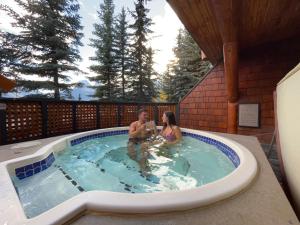 a man and woman sitting in a swimming pool at A Bear and Bison Country Inn in Canmore
