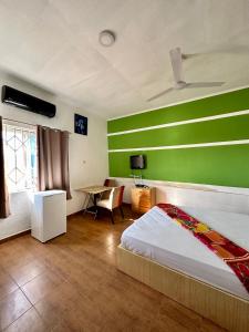 1 dormitorio con una pared verde, cama y escritorio en My Place Guest House, en Ho