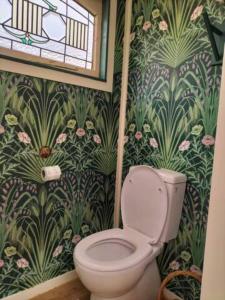 a bathroom with a toilet and floral wallpaper at Casa Tavaita in Karangahake gorge in Paeroa