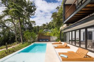 une piscine extérieure avec des chaises et une maison dans l'établissement Casa Maleku of Joya Luxury Estate, à Santa Teresa