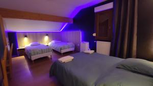 um quarto com 2 camas e uma iluminação roxa em Logis auberge de la Poirie em Tendon